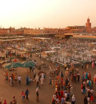 Vista panorámica de la Plaza Jemaa el-Fna en Marrakech, con multitudes disfrutando de la diversidad cultural y el entretenimiento callejero.