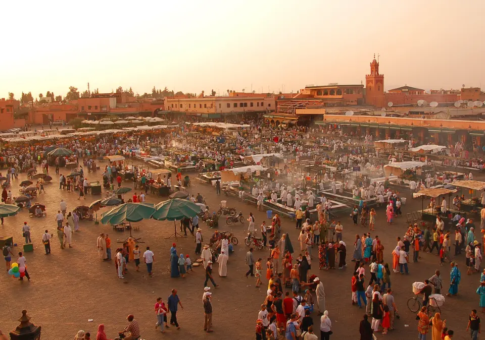 Vista panorámica de la Plaza Jemaa el-Fna en Marrakech, con multitudes disfrutando de la diversidad cultural y el entretenimiento callejero.