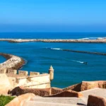 Imagen de la Playa de Rabat con el sol brillando sobre la arena dorada y el mar atlántico en el horizonte