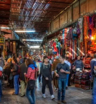 Vista colorida y bulliciosa de los Zocos de Marrakech, con vendedores y clientes explorando las tiendas y puestos